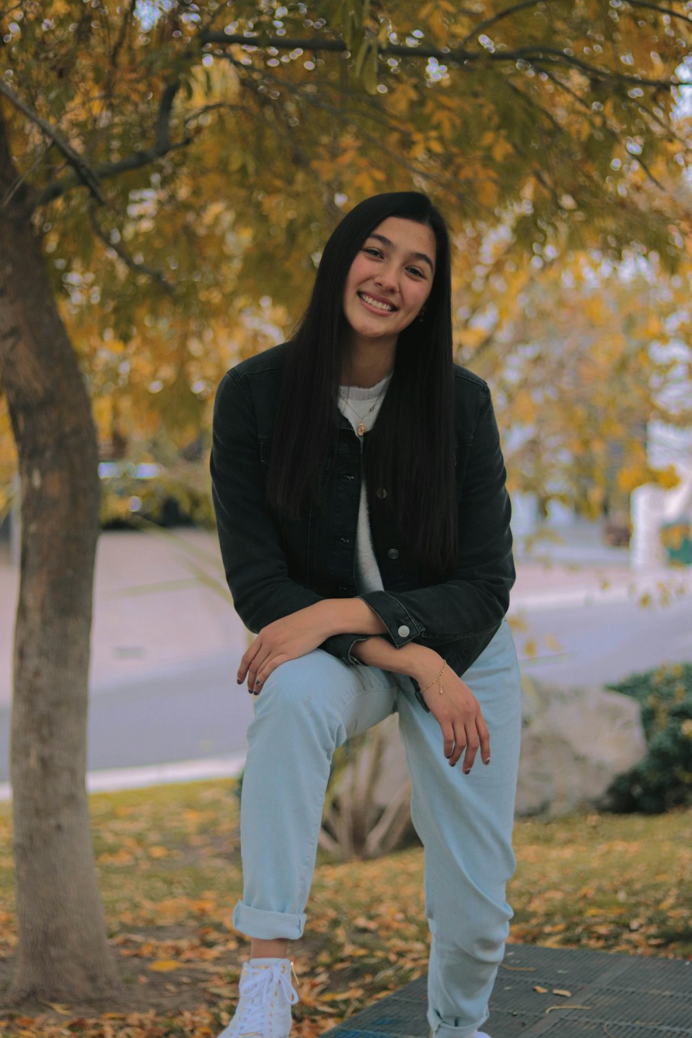 a woman sitting on a bench in front of a tree