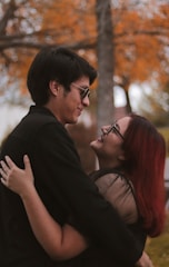 Couple laughing together under a canopy of autumn leaves.