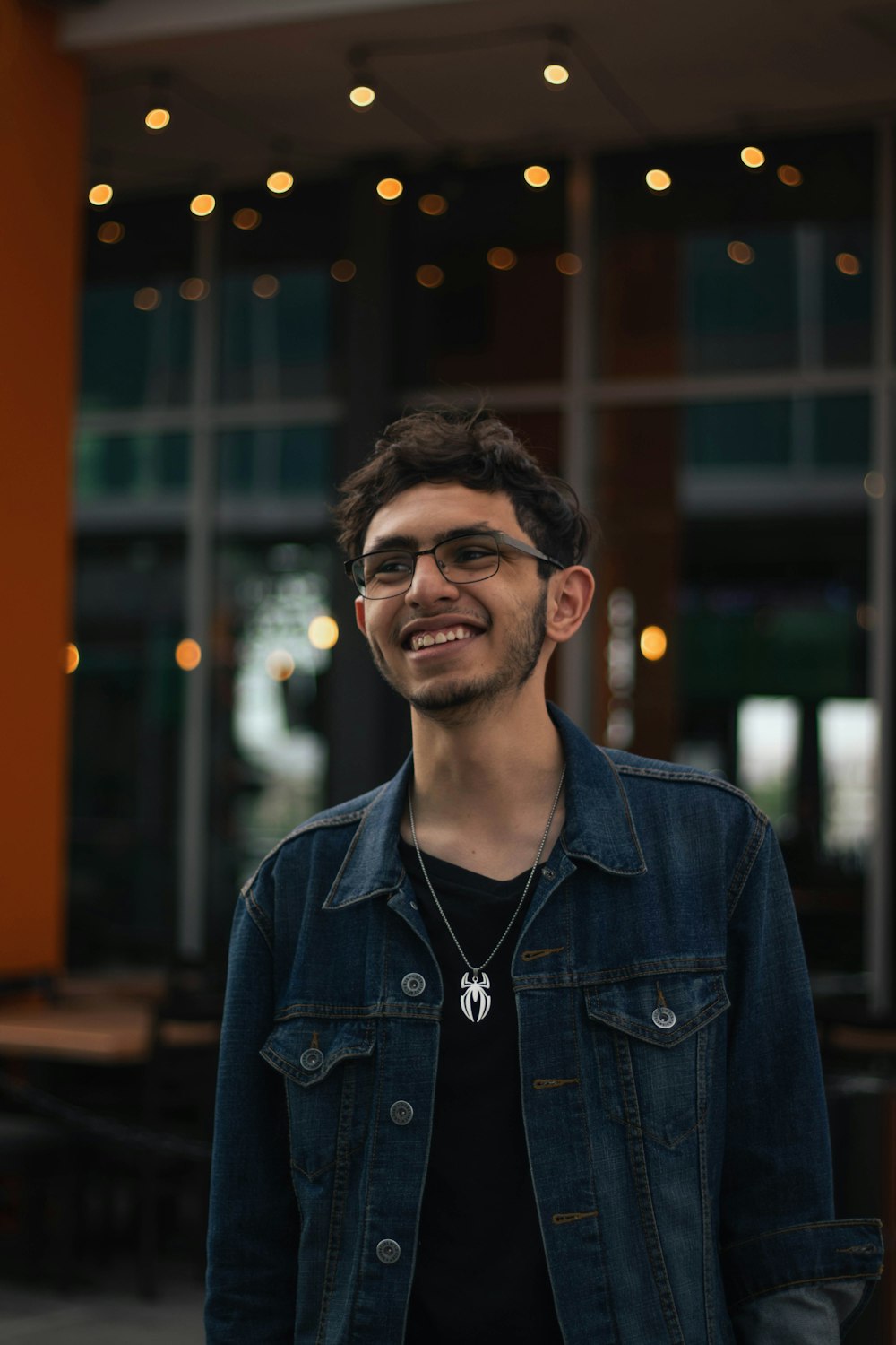 a man with glasses standing in front of a building