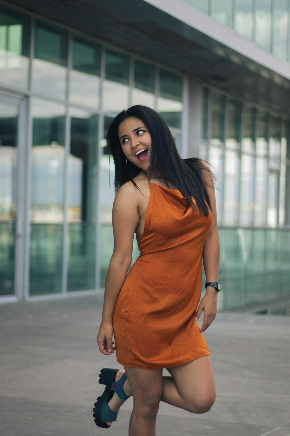 a woman in an orange dress posing for a picture