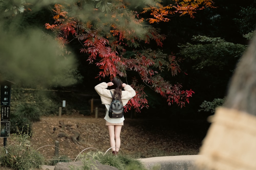 a woman standing in front of a red tree