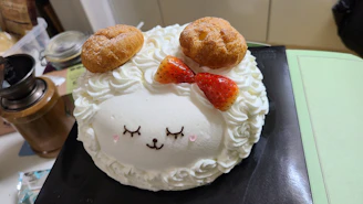 a cake with a sheep face and two donuts on top of it