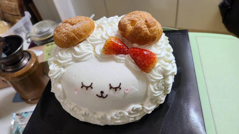 a cake with a sheep face and two donuts on top of it