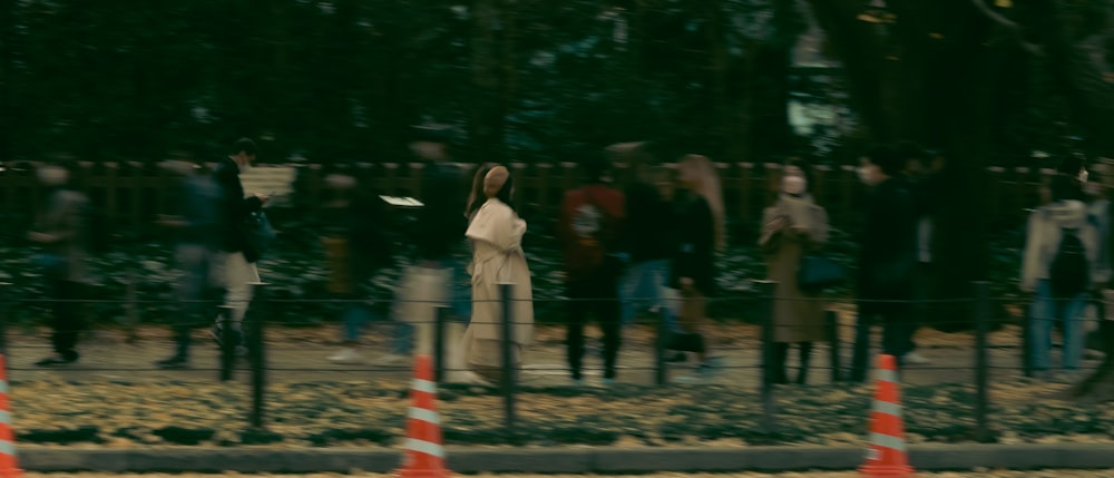 a group of people standing next to a fence