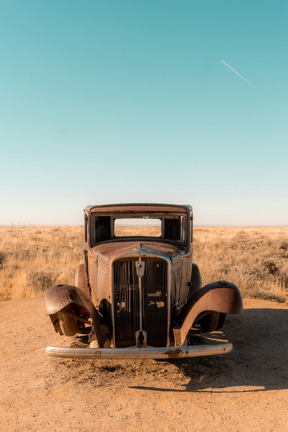 an old car sitting in the middle of the desert