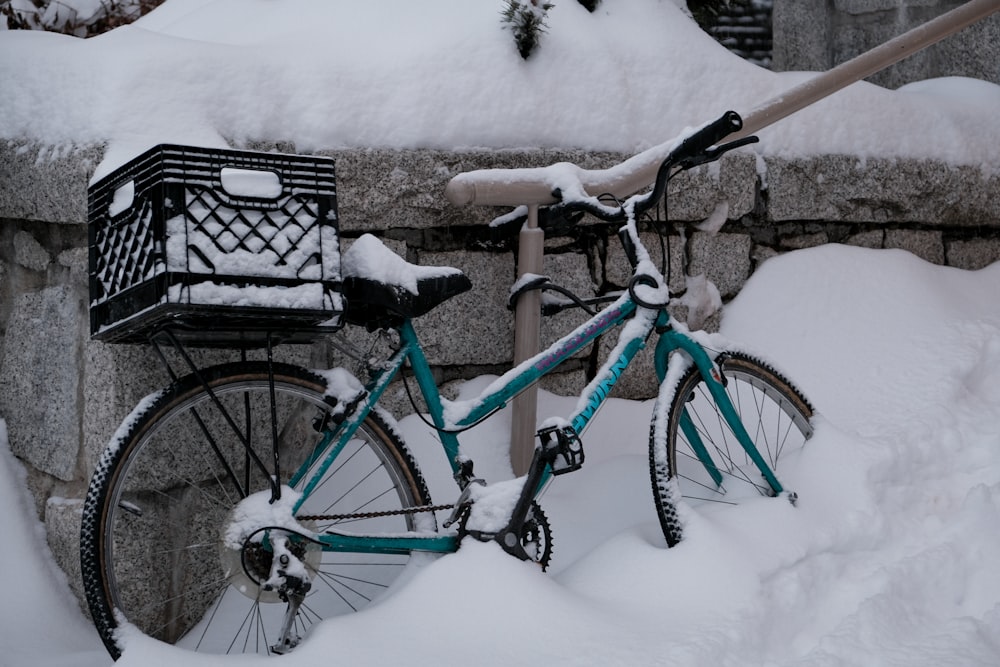 a bicycle is covered in snow next to a stone wall