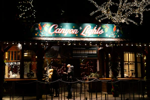 Kids excitedly putting on the green surrounded by lush trees and festive lights in Radium Hot Springs