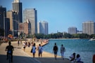 a group of people walking down a sidewalk next to a body of water