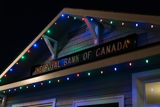 A building facade displaying 'The Royal Bank of Canada' sign, adorned with colorful string lights in blue, red, green, and yellow hues.