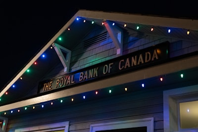 A building facade displaying 'The Royal Bank of Canada' sign, adorned with colorful string lights in blue, red, green, and yellow hues.
