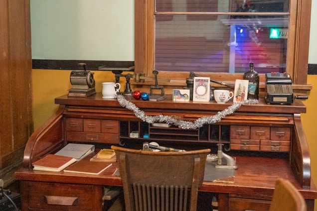 A cozy wooden desk scattered with colorful vintage postcards and an old-fashioned ink pen.