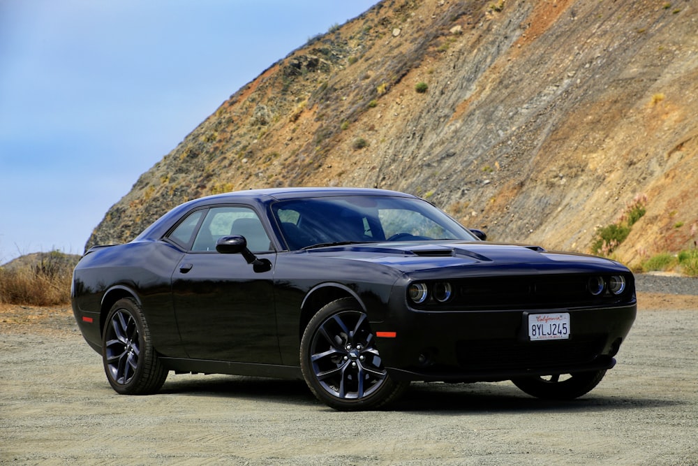 a black car parked in front of a mountain