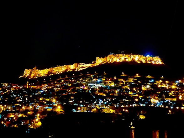 A sprawling walled city under a twilight sky, with shadowy figures lurking beyond the walls.