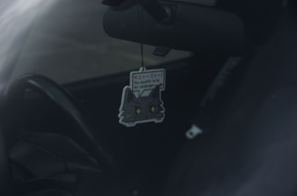 A sleek car interior with a stylish Carfumes air freshener hanging from the rearview mirror.