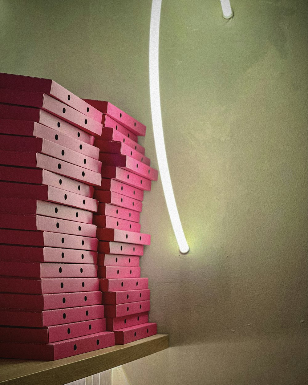 a stack of pink boxes sitting on top of a wooden shelf