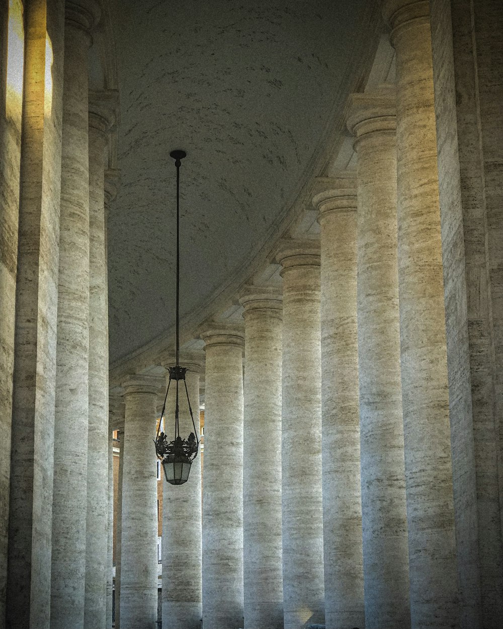 a room with columns and a chandelier hanging from the ceiling