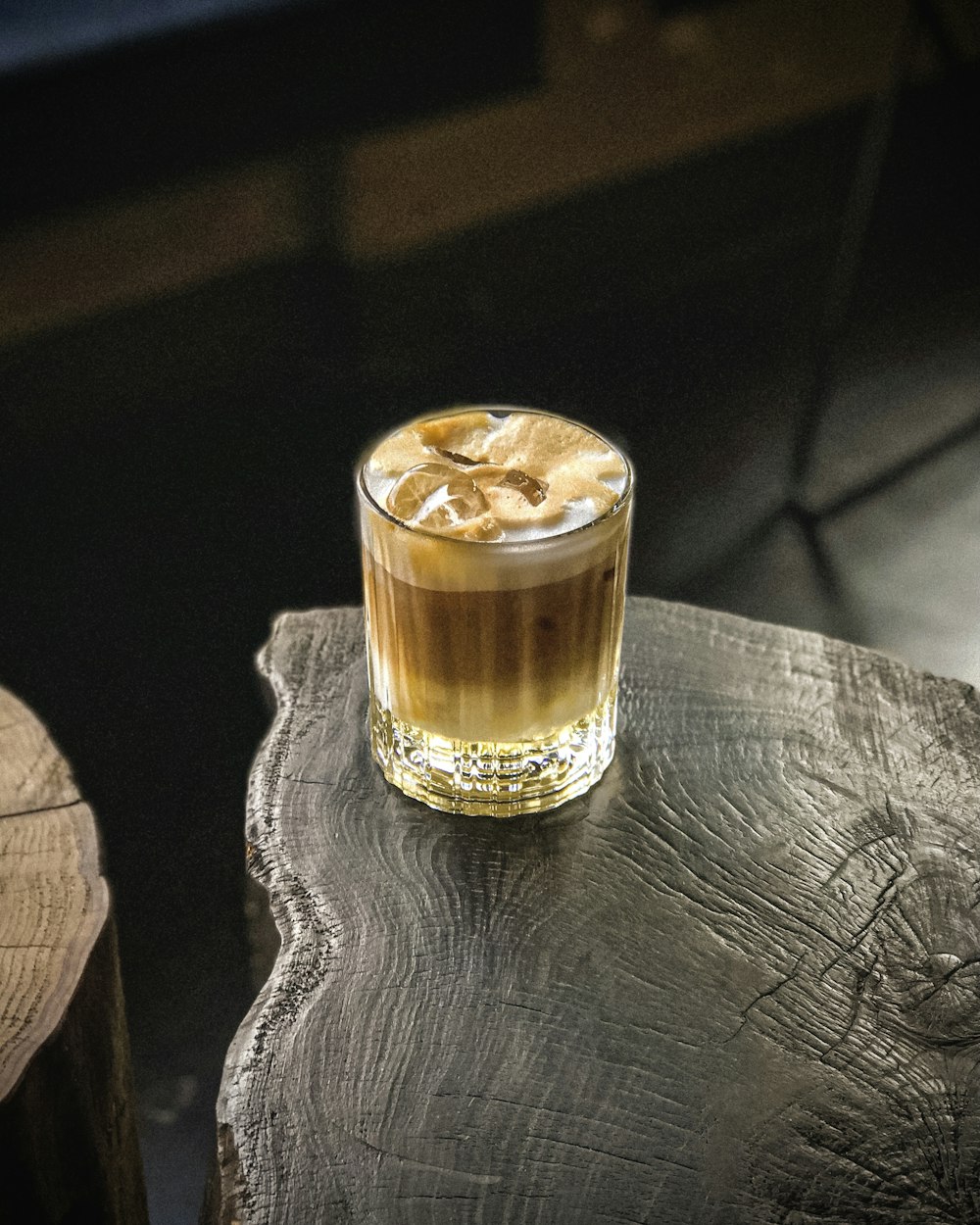 a glass filled with liquid sitting on top of a wooden table