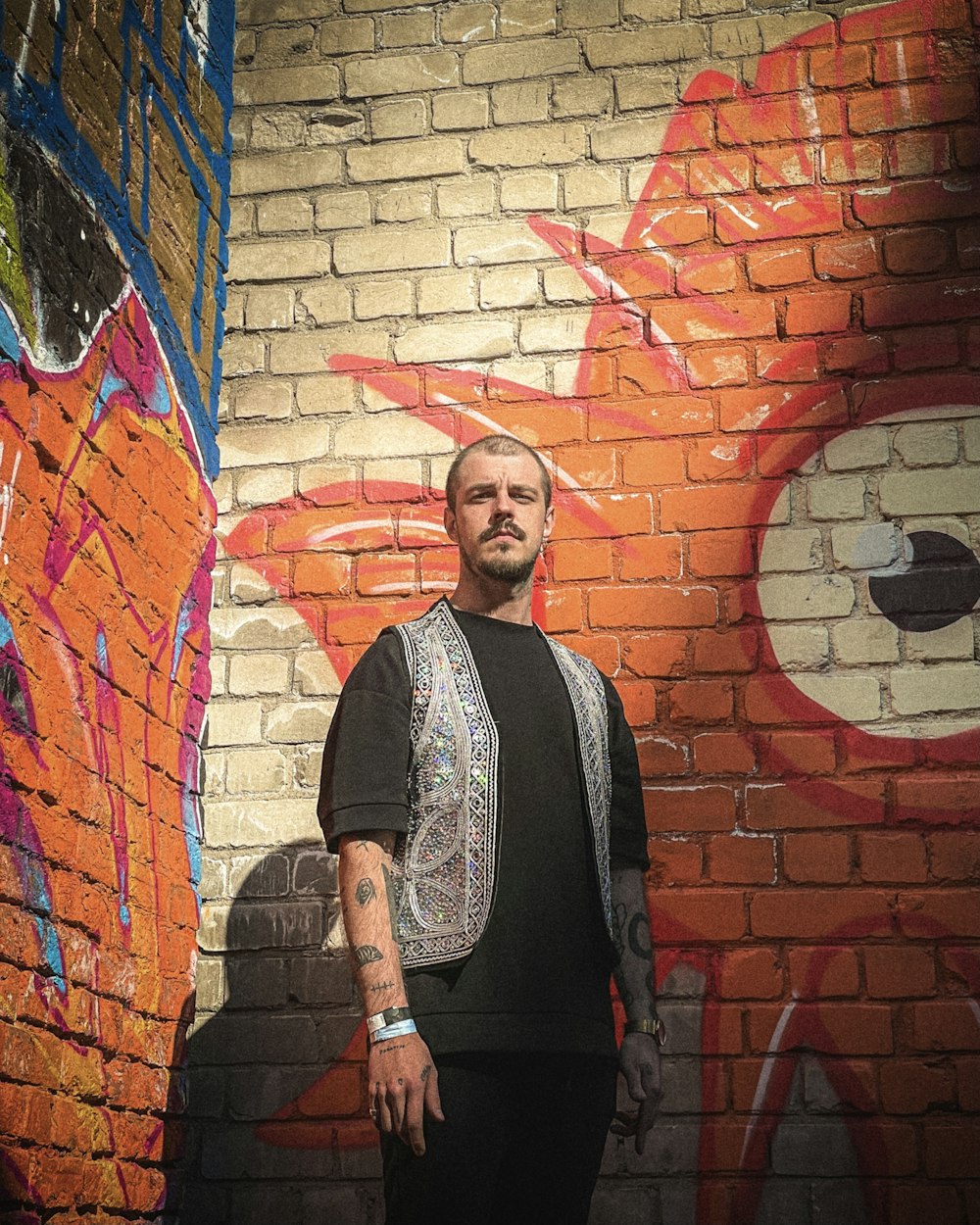 a man standing in front of a brick wall