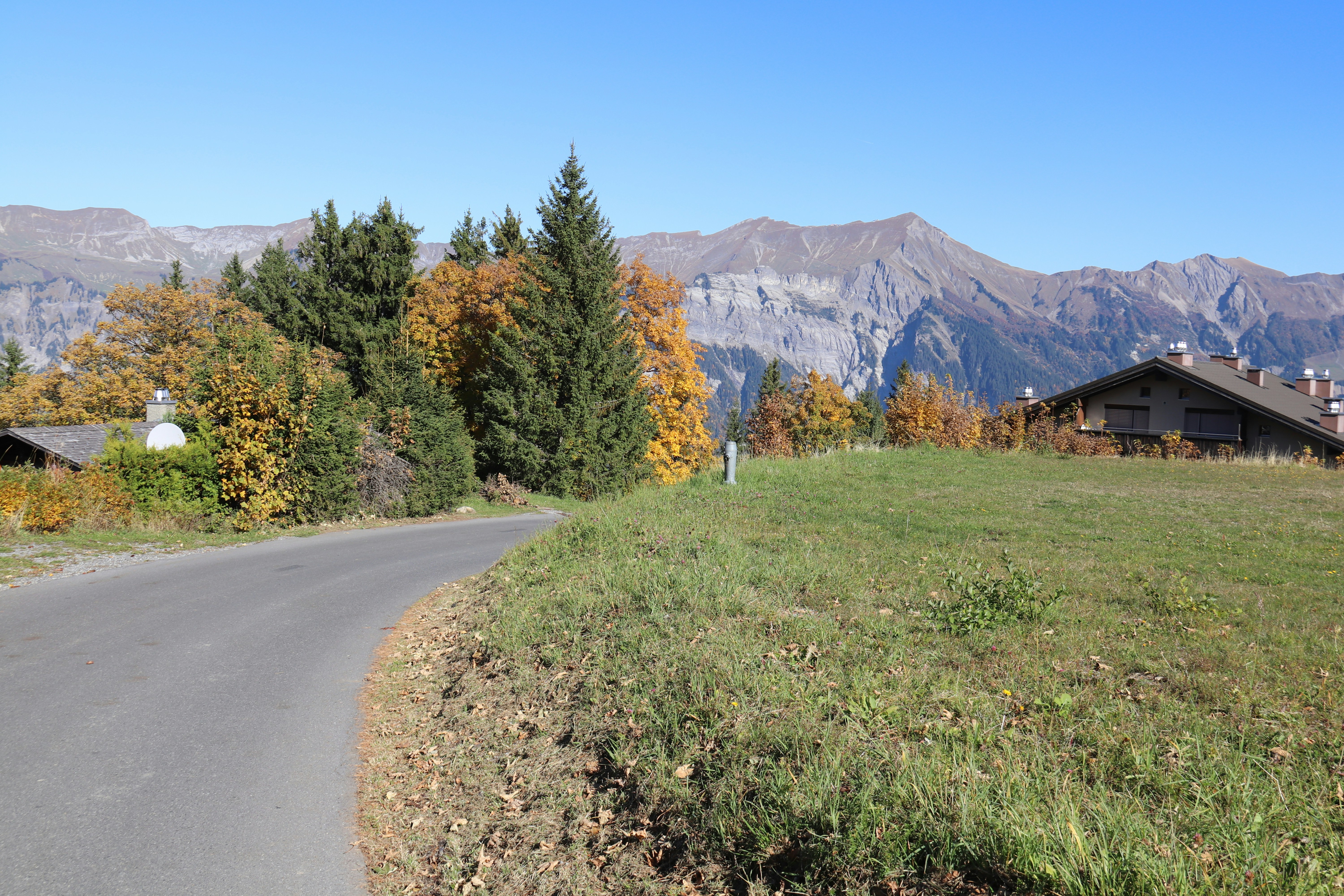 a winding road in the mountains with a house in the distance