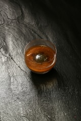 a small bowl of sauce on a black surface