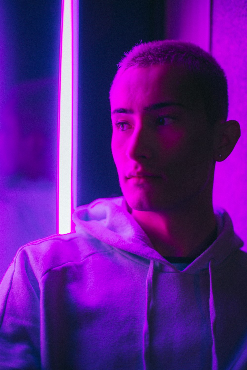 a man in a hoodie standing in front of a purple light
