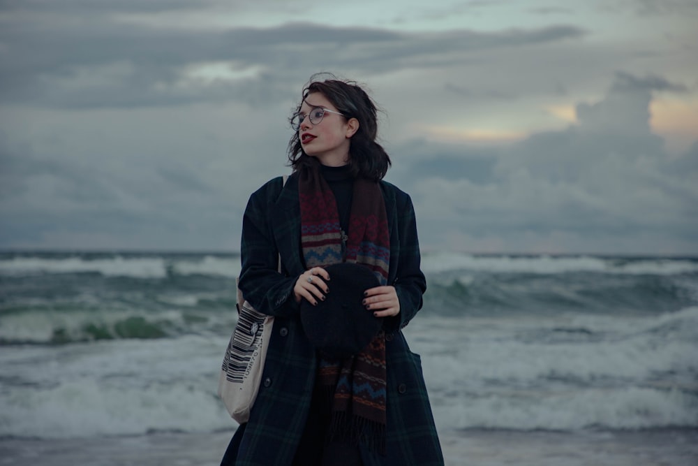 a woman standing on a beach next to the ocean