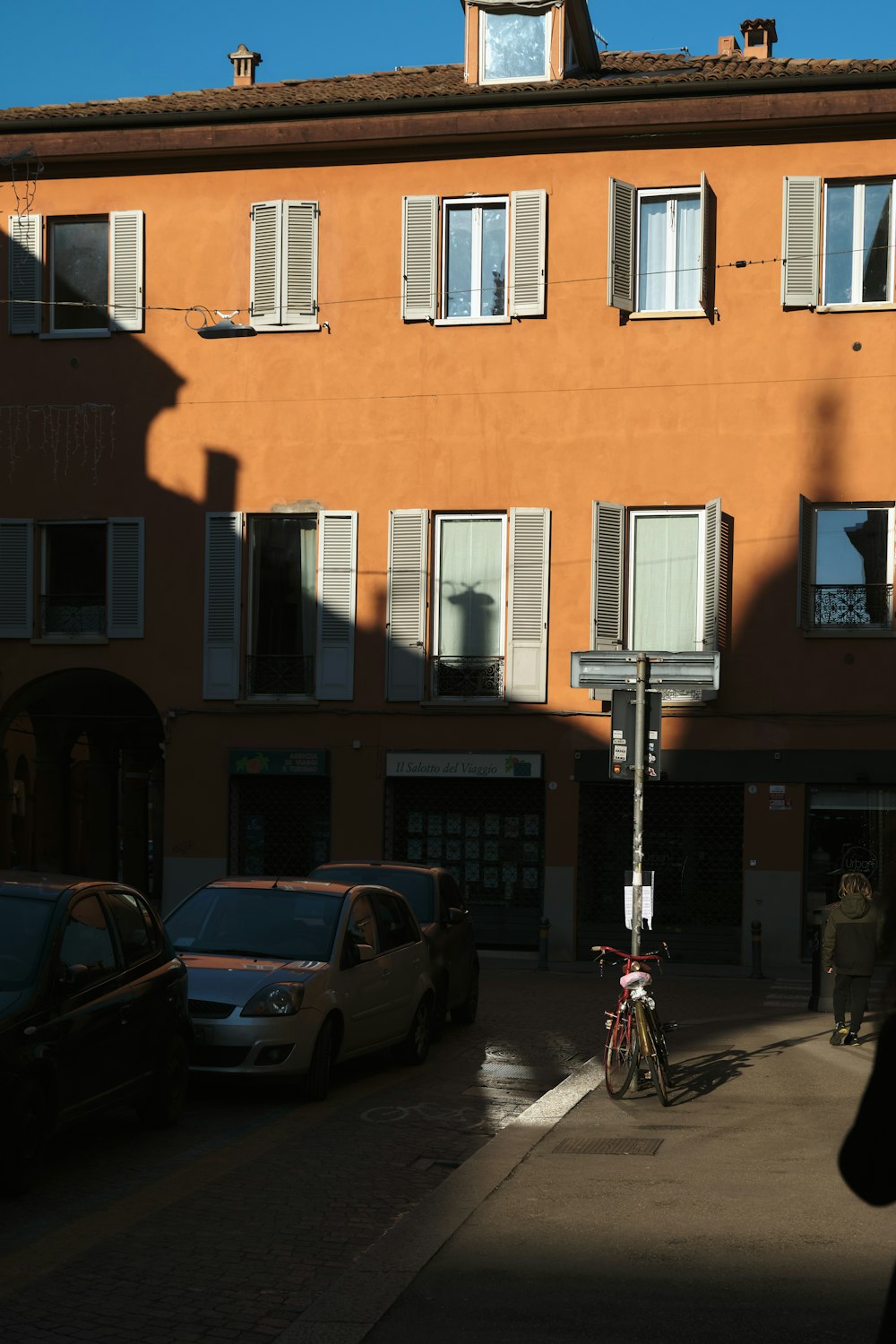 Eine Person, die eine Straße neben einem hohen Gebäude entlang geht