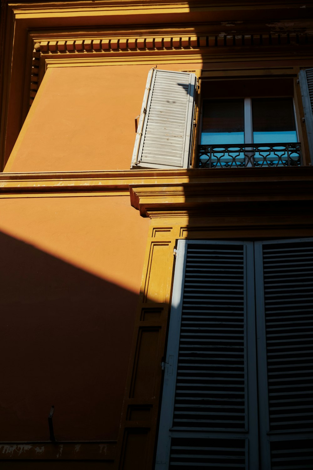 a yellow building with a window and shutters