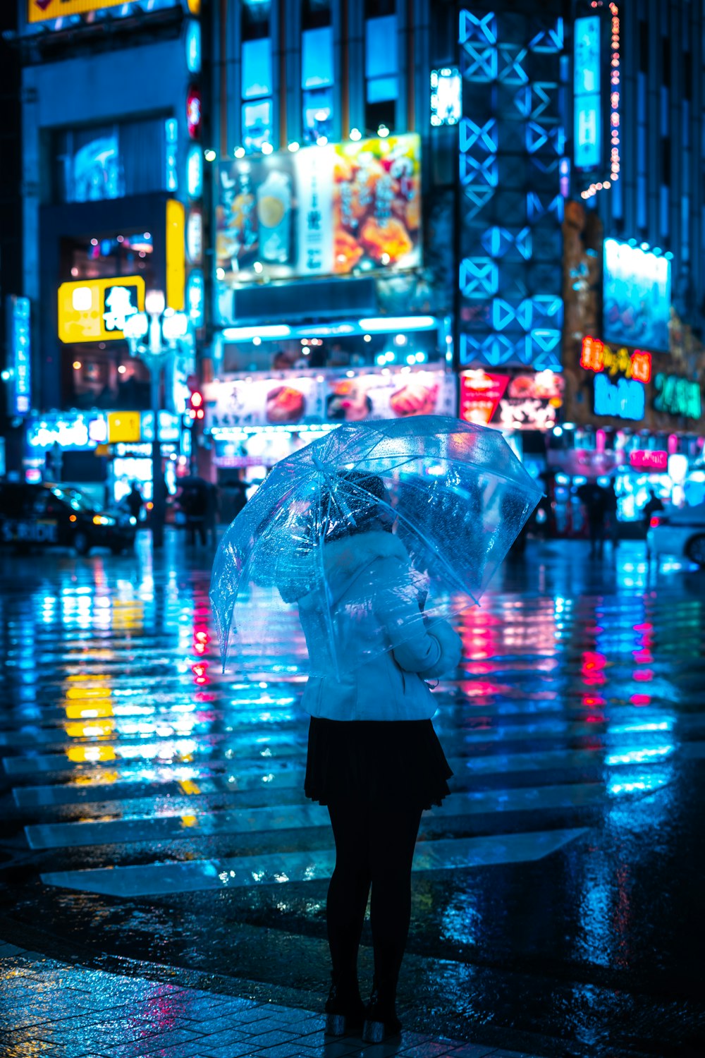 a woman holding an umbrella on a city street at night