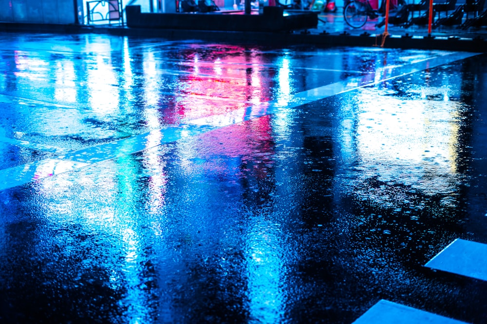 a wet street with a red umbrella and a blue umbrella