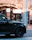 A stylish black SUV parked outside a concert venue at dusk with happy passengers stepping out.