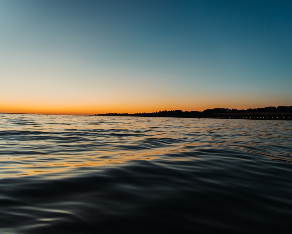 Un cuerpo de agua con una puesta de sol en el fondo