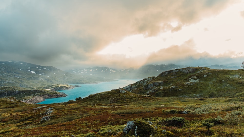 a large body of water sitting on top of a lush green hillside