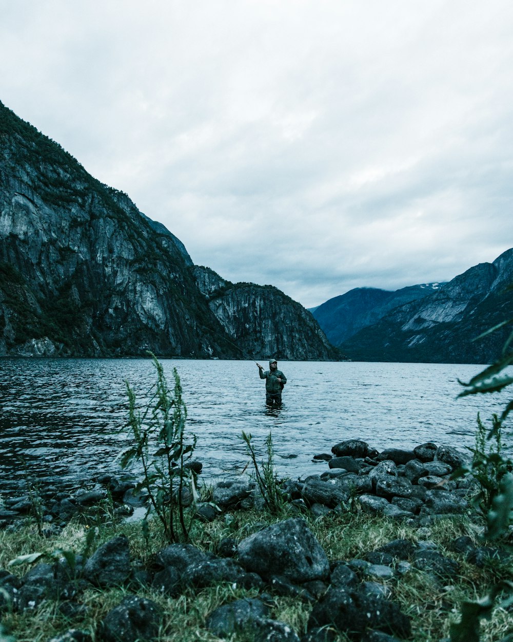 a man standing in a lake surrounded by mountains