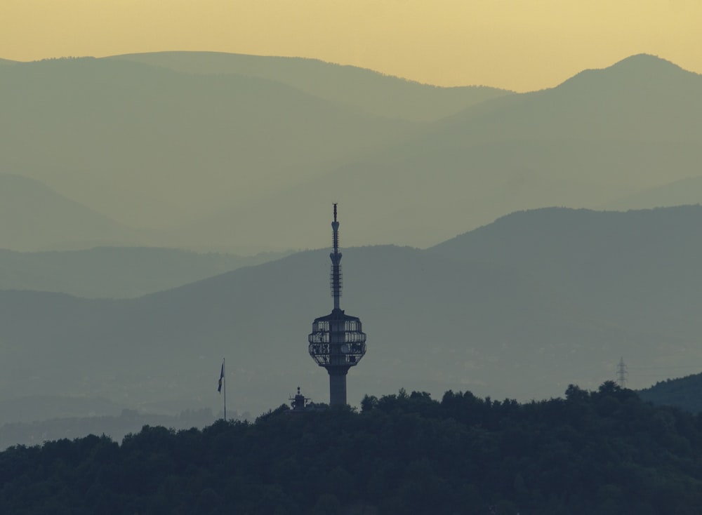 a tower on top of a hill with a mountain in the background