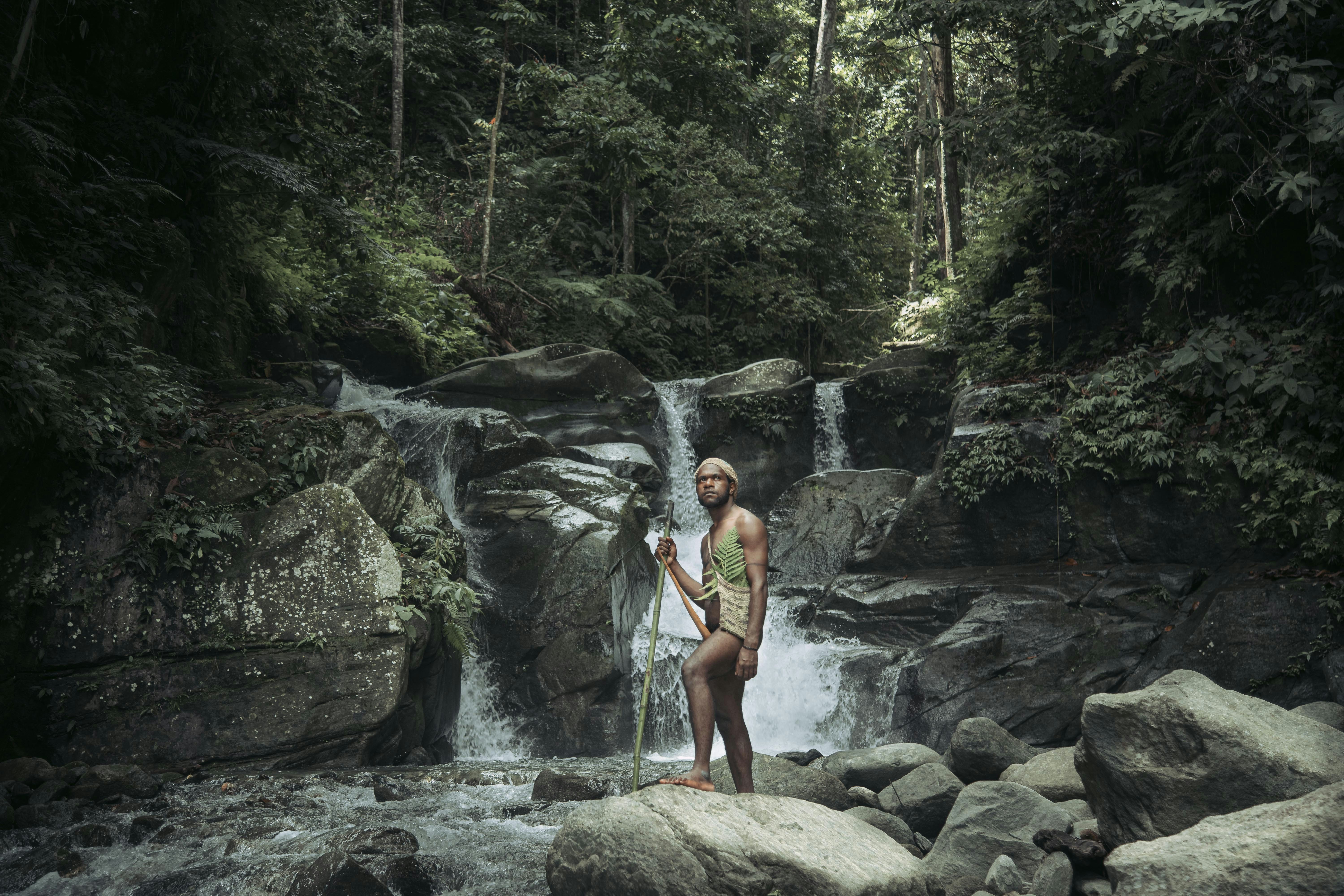 a man standing on rocks in front of a waterfall