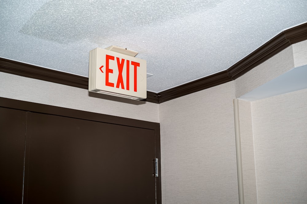 a red exit sign mounted to the ceiling of a bathroom
