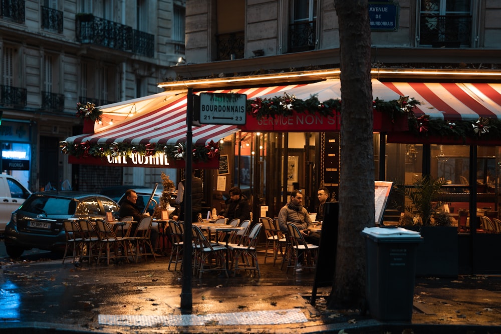 a group of people sitting at a table outside of a restaurant