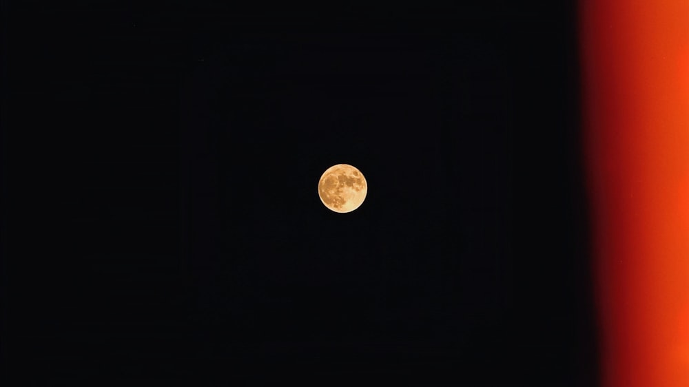 a full moon is seen in the dark sky