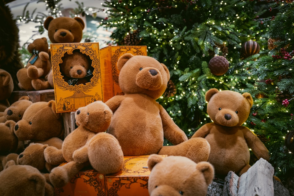 a pile of brown teddy bears sitting next to a christmas tree