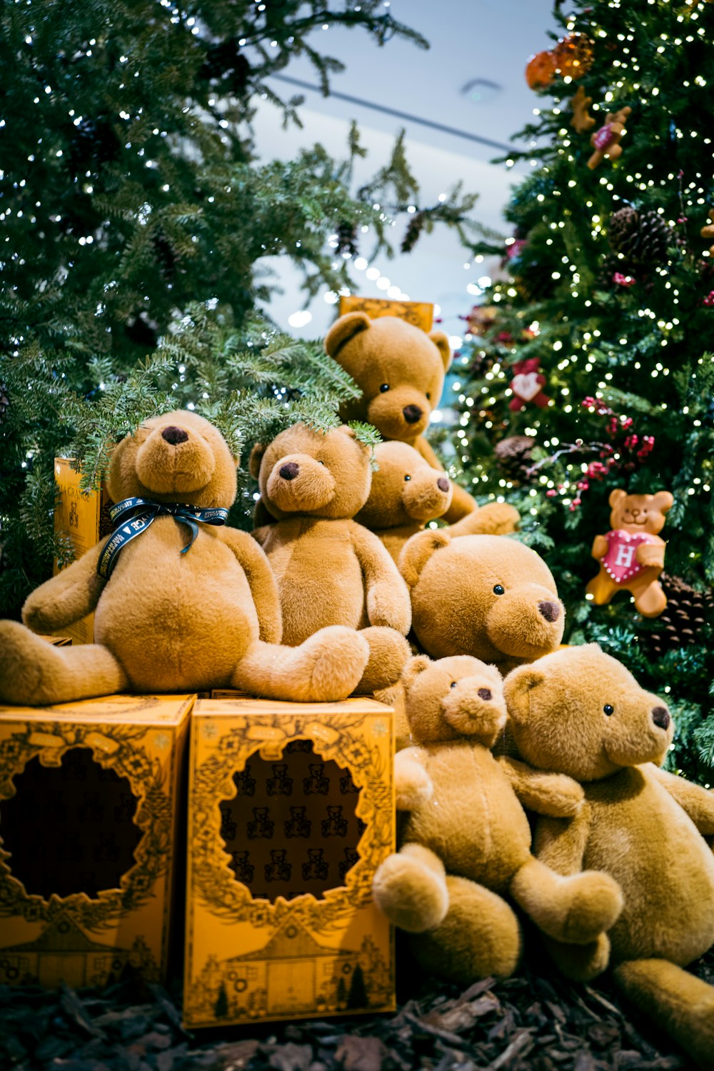 a pile of teddy bears sitting next to a christmas tree