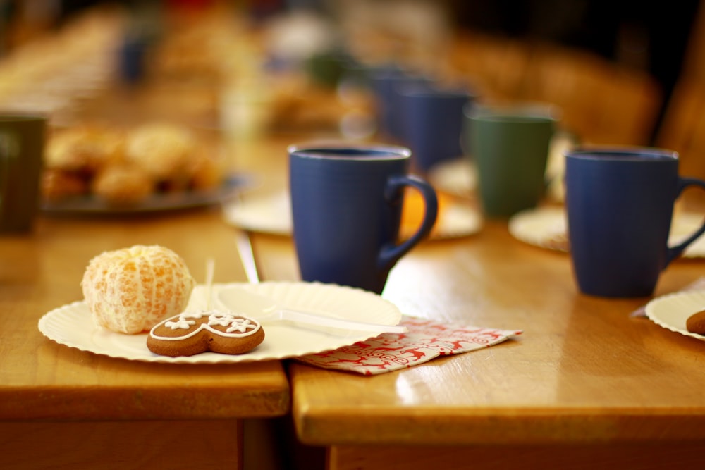 a wooden table topped with plates of food and cups of coffee