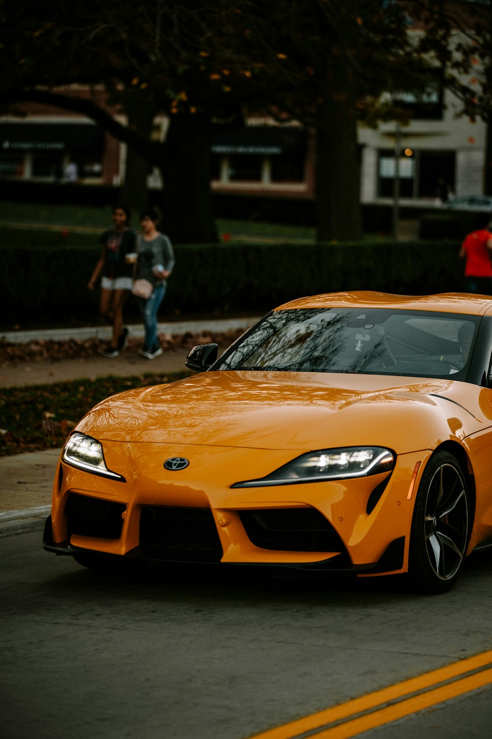 an orange sports car parked on the side of the road