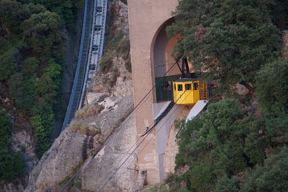 a yellow train traveling down train tracks next to a forest