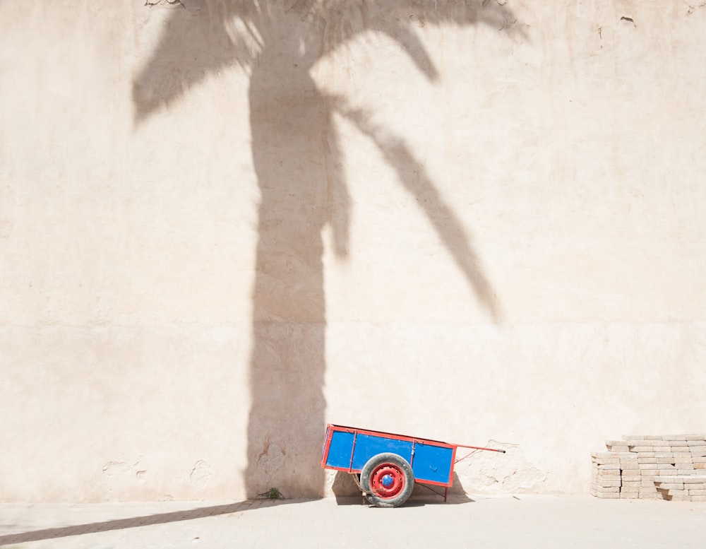 a red, white and blue wagon sitting in front of a palm tree