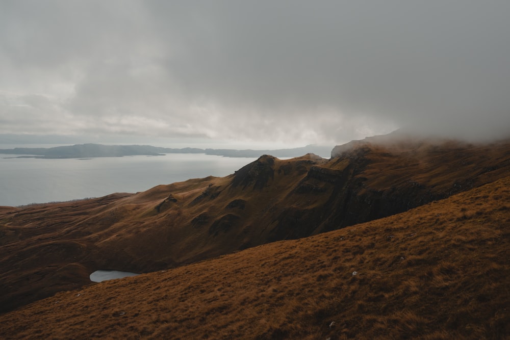 a foggy mountain with a body of water in the distance