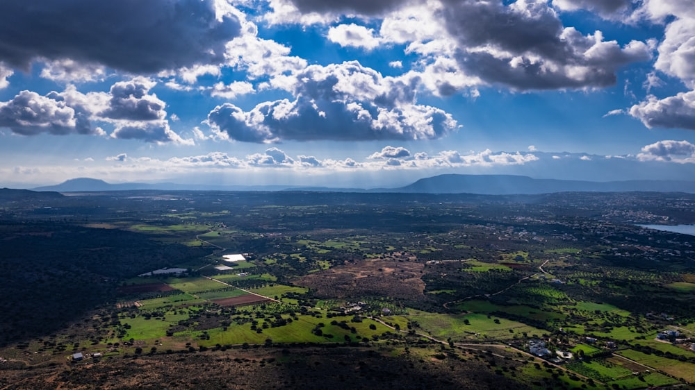 an aerial view of a green field and mountains