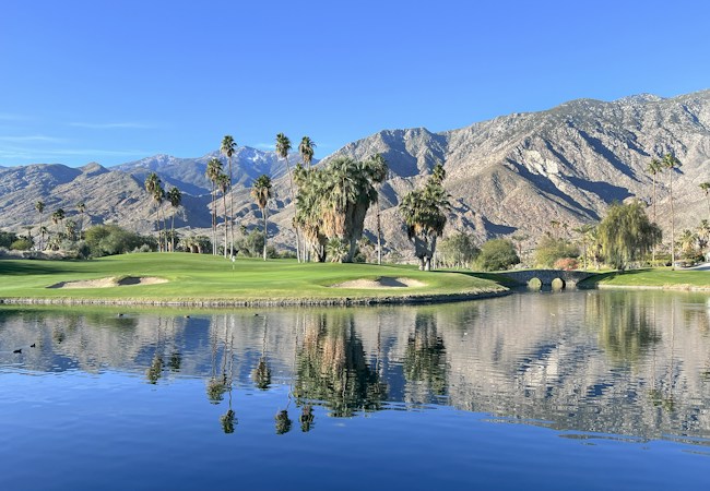 A golf course with a water feature and mountains in the background, similar to the desert golf setting found in Henderson