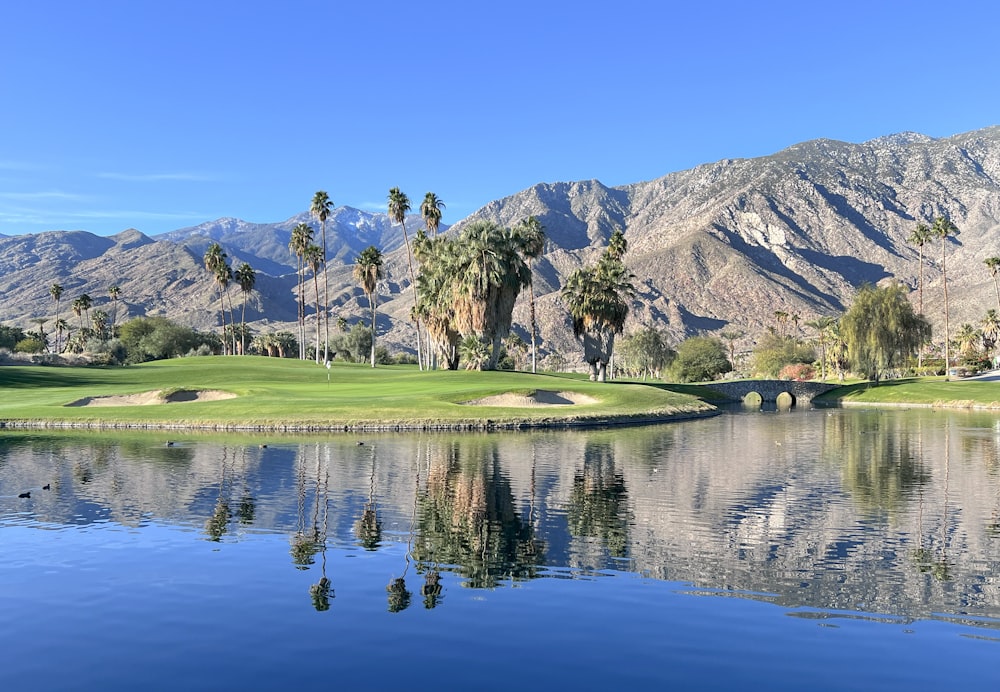 a golf course with a lake and mountains in the background