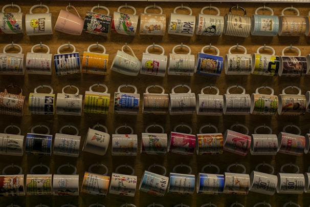 A variety of mugs featuring unique designs on a wooden table.